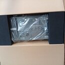 V kartonové krabici s černou pěnovou výplní leží kytarový procesor zabalený v průhledné plastové fólii. Na zařízení je vidět bílé logo NUX a označení…
