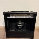 Zadní strana černého kytarového komba v přepravním pouzdře. Na zadním panelu je bílý štítek s nápisy LINE 6, SPIDER III 15 AMPLIFIER - 15 WATTS 1 X 8…