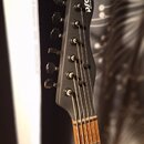 Černá hlava elektrické kytary s šesti ladicími kolíky. Na horní části je bílý nápis psd Guitars. Hmatník je vyroben z dřeva s viditelnou strukturou s…