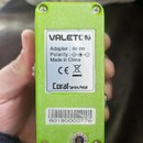 Zadní strana zeleného efekt pedálu značky VALETON. Na bílém štítku je uveden nápis „Adapter : 9V“, „Polarity : ⊕-C-⊖“, „Made in China“, logo CE, symb…