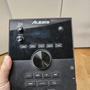 Černý elektronický modul s nápisem ALESIS v horní části a CRIMSON II v levém dolním rohu. V pravém dolním rohu je text ADVANCED DRUM MODULE. Zařízení…