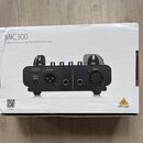 Fotografie znázorňuje bílé papírové krabice s produktem. Na krabici je nápis MIC300 a text Audiophile Vacuum Tube Preamplifier with Limiter. V pravém…
