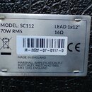 Kovový štítek s technickými údaji připevněný na černý texturovaný povrch. Na štítku je uveden nápis MODEL: SC112, 70W RMS a LEAD 1x12" 16Ω. Je zde čá…