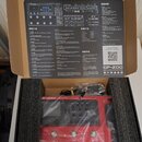 Červený multi-efektový procesor s nápisem GP-200 MULTI-EFFECTS PROCESSOR, umístěný v originální krabici s polystyrenovými vložkami a zabalený v plast…