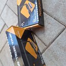 Dvě krabice s produktem BeamZ DMX TRANSCEIVER. Balení jsou černé a oranžové s nápisy „7 UNIVERSES“ a „UNPACK. INSTALL. AMAZE.“. Na krabicích je zobra…