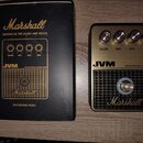 Fotografie zobrazuje distortion pedál Marshall JVM Distortion & Noise Gate v originální černé krabici. Pedál má zlatý kovový horní panel se čtyřmi ov…