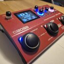 Červený vokální procesor značky BOSS, model Vocal Performer VE-22. Zařízení má digitální displej s nápisem 01 A1 ROCK preset a několik ovládacích kno…