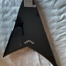 Zadní strana černé elektrické kytary s V-tvarem korpusu. Na kovovédesce u krku je nápis Gibson a pod ním text MADE IN USA. Na korpusu jsou vidět pět…