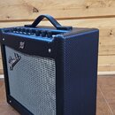 Černý kytarový kombozesilovač s šedou textilní přední mřížkou. Na mřížce je umístěno stříbrné logo Fender. Horní ovládací panel obsahuje několik čern…