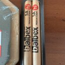 Dvě dřevěné bubnové paličky v černém obalu. Na paličkách je uveden nápis Balbex, označení 5A a text PREMIUM HICKORY. V horní části obalu je štítek s…