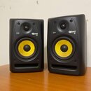 Dva černé studiové monitory s žlutými membránami basových reproduktorů. Na obou je vidět logo KRK a nápis ROKIT 5. Povrch krytů je matný, v dolní čás…