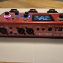 Červený vokální procesor značky BOSS, model VE-22. Na zadním panelu jsou vidět konektory INPUT MIC (XLR), OUTPUT R a L/MONO, PHONES/LINE OUT, AUX IN,…