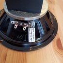 Černý reproduktor s kovovým rámem a stříbrným magnetem. Na rámu je bílá nálepka s nápisy „Weber SPEAKERS 127“, „MODEL 8A10D“, „OHMS 15 WATTS“ a „DATE…