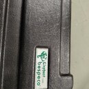 Detail černého tvrdého pouzdra s texturovaným povrchem. Na boku je nalepená bílá nálepka s logem slona a zeleným nápisem Elephant bespeco cases®. Pov…