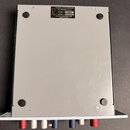 Fotografie zachycuje spodní stranu šedého kovového zařízení. Na horní části je nalepený štítek s nápisy: RUPERT NEVE DESIGNS, The FORTEXO SERIES, MOD…