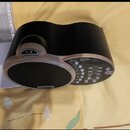Černý přístroj DR-01s Rhythm Partner s ovládacími prvky na horní straně. Na boku je viditelné logo BOSS. Vedle přístroje leží uživatelský manuál s ná…