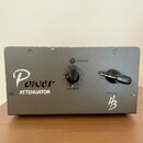 Šedý kovový box s nápisem Power ATTENUATOR a logem HB v pravém dolním rohu. Na přední straně jsou dva černé otočné ovladače s popisky Line Level a SP…