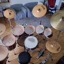 Celá bicí souprava v červeném provedení s kovovými stojany a černým sedákem. Na několika činelech je vidět logo Paiste a na největším činele nápisy Z…