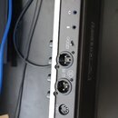 Detail zadního panelu stříbrného elektronického zařízení s černým šasi. Jsou zde vidět konektory s popisky OUTPUT, L (MONO), symboly sluchátek a USB,…