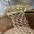 Detail kovového mechanismu s nápisem MADE IN JAPAN. Kolem je vidět chromovaný povrch a připevněná kovová síťka. Povrch vykazuje známky opotřebení a d…