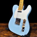 Světle modrá elektrická kytara typu Telecaster s bílým pickguardem a hnedým javorovým hmatníkem. Na kovovém krytu snímače je nečitelný nápis. Povrch…