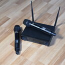 Dva černé bezdrátové mikrofony a černý přijímač se dvěma anténami na dřevěné podlaze. Na tělech mikrofonů je bílý nápis „InZone“. Přijímač má na před…