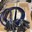 Modrý vícežilový kabel (snake cable) svedený do několika černých konektorů. Na plášti kabelu je bílý nápis „28 AWG 8 PAIR STAGE SNAKE CABLE“. Konekto…