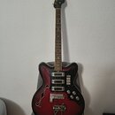 Elektrická kytara s polodupatým korpusem v červeně-černém sunburst provedení. Na hlavě hmatníku je viditelné logo Samick. Nástroj má dva snímače, čty…