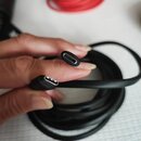 Černý kabel s konektory USB-C na obou koncích. Kabel je svinutý do klubíčka a drží ho ruka. Na konektorech nejsou žádné viditelné značky ani nápisy.