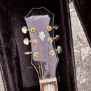 Černá hlava kytary značky Epiphone s bílým logem a ozdobnou perleťovou vložkou ve tvaru koruny. Na zadní straně hlahy je viditelný nápis EJ. Nástroj…