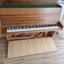 Dřevěný piano v hnědé barvě s otevřeným víkem a vyklopeným pedálovým prostorem. Na přední části nad klávesnicí je umístěn nápis ZIMMERMANN. Klávesnic…