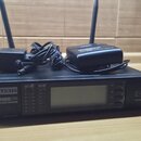 Černý bezdrátový přijímač s dvěma anténami. Na přední straně je nápis LD SYSTEMS a model WS1000G2R UHF PLL DIVERSITY WIRELESS RECEIVER. Na přístroji…