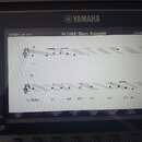 Fotografie zachycuje displej digitálního klavíru značky YAMAHA. Na obrazovce je zobrazen notový zápis s nadpisem SCORE: Blues, Katapult a označením P…