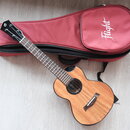 Dřevěný akustický nástroj typu ukulele v přirozené barvě s černým lemováním. Na hlavě hmatníku je bílé logo znázorňující stylizované písmeno S. Vedle…