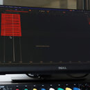Fotografie zachycuje monitor značky DELL, na kterém je otevřený program pro nahrávání a editaci zvuku s červenými audio stopami. Pod monitorem je umí…