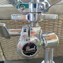 Detail chromovaného mechanismu stojanu značky Pearl. Na vřeteni je vidět nápis „Pearl“ a na kulatém krytu mechanismu je logo „Pearl“ s doplňujícím te…