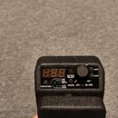 Černý elektronický přístroj s digitálním displejem a ovládacím knoflíkem. Na panelu jsou nápisy OUTPUT SELECT, SAVE, LOAD, PARAMETER, TYPE CHAN, SHAP…