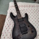 Elektrická kytara s tmavě hnědým, průhledným lakem a výraznou strukturou dřeva na topu. Nástroj má dva černá humbuckery, prohýbatelný most a dva ovlá…