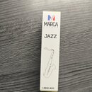 Bílá obdélníková krabička s nápisy a grafikou. V horní části je barevné logo ve tvaru písmene M a text MARCA FRANCE, uprostřed je napsáno JAZZ. Ve sp…