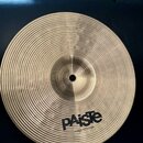 Kruhový činel z mosazného kovu s výrazným koncentrickým žebrováním po celém povrchu. V dolní části je černé logo PAiste a pod ním menší nápis MADE IN…