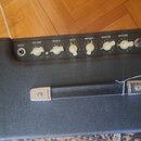 Černý kytarový kombozesilovač s texturovaným povrchem a černým ovládacím panelem. Na panelu jsou bílé nápisy INPUT, VOLUME, TREBLE, BASS, MIDDLE, MAS…