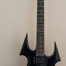 Černá elektrická kytara s ostře hranatým korpusem a černým hmatníkem. Na hlavě je bílý nápis " Harley Benton ". Nástroj má dva humbuckery, jeden ovlá…