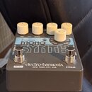 Šedý kytarový efekt s bílými oválnými knoflíky. Na horní straně je nápis bass MONO SYNTH a v dolní části značka electro-harmonix NEW YORK CITY, USA.…