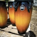 Tři kongy s přechodovým lakováním od černé barvy v horní části po žlutou v prostřední a opět černou u spodního okraje. Na každém nástroji je bílé kul…