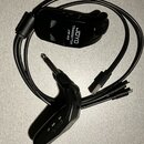 Černý bezdrátový vysílač s připojeným kabelem a USB konektorem. Na zařízení je bílý nápis JOYO TRANSMITTER JW-03 a přepínač s označením ON OFF. Povrc…