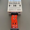 Červená DI box s černými gumovými rohy a nápisy v bílé barvě. Na zařízení jsou vidět označení MODEL GI100, PAD -20 dB, CLIP -20 dB a PHANTOM POWERED…