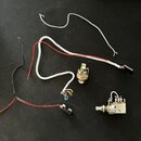 Fotografie zobrazuje elektronické součástky a zapojení z hudebního nástroje. Jsou zde dva potenciometry s připojenými vodiči v různých barvách (černá…