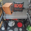 Černý skládací stojan na klávesy s nápisem MIDEX na středové vzpěře. Na stojanu je umístěn dřevěný subwoofer v hnědé barvě s nápisem B&W. V pozadí je…