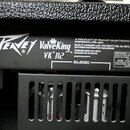 Detail zadní části kytarového komba s černým texturovaným povrchem. Na černém štítku jsou bílé nápisy Peavey®, ValveKing VK 112 TM, A PRODUCT OF PEAV…