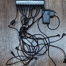 Černý napájecí rozdělovač s nápisem ENGL Power Tap. Zařízení má deset výstupů DC, do kterých jsou zapojeny černé kabely s úhlovými konektory. K rozdě…
